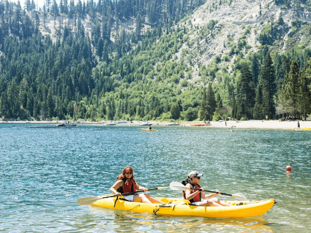 Two female friends row in a dual kayak on Lake Tahoe in Emerald Bay