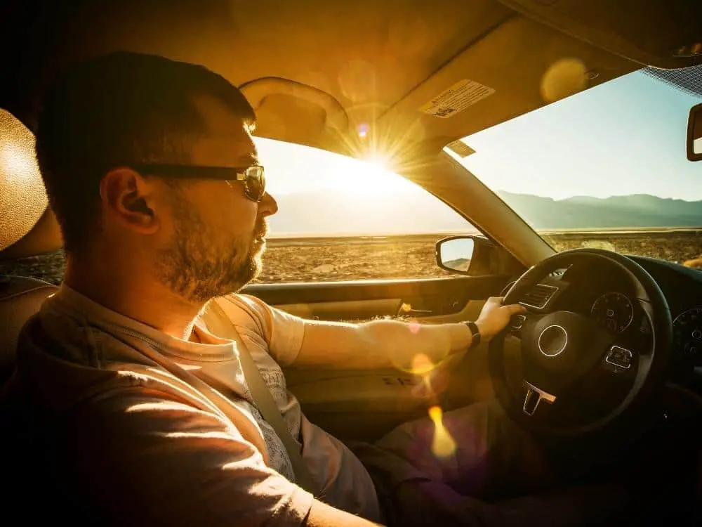 Man driving through Southern California deserts with mountains behind - California Places, Travel, and News.