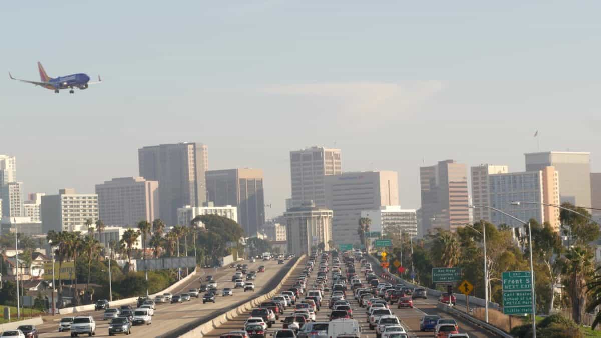 SAN DIEGO CALIFORNIA USA 15 JAN 2020 Busy intercity freeway traffic jam on highway during rush hour. Urban skyline highrise skyscraper and landing plane. - California Places, Travel, and News.