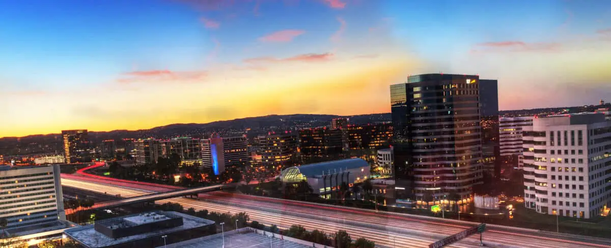 Sunrise over a highway in Irvine California as headlight trails move through the roadways. - California Places, Travel, and News.