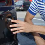 Car damaged in parking lot. Man checking car scratches and dents - California Places, Travel, and News.