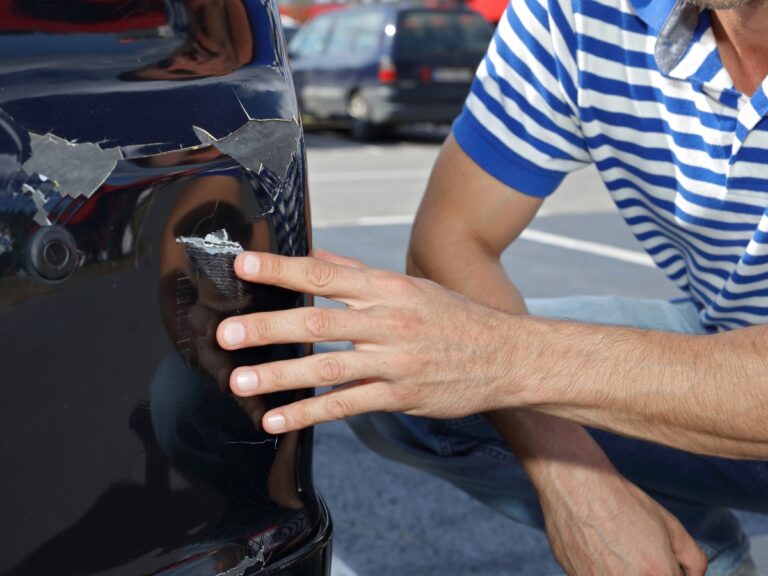 Car damaged in parking lot. Man checking car scratches and dents - California Places, Travel, and News.